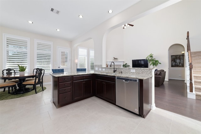 kitchen with light stone counters, dishwasher, sink, light tile patterned flooring, and dark brown cabinetry