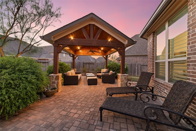 patio terrace at dusk featuring a gazebo, ceiling fan, and outdoor lounge area