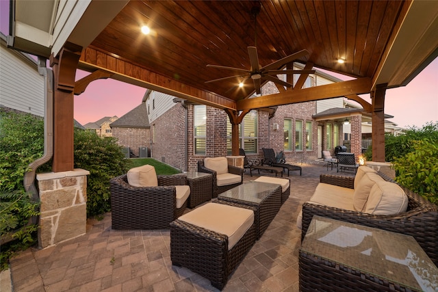 patio terrace at dusk with a gazebo, ceiling fan, and an outdoor living space