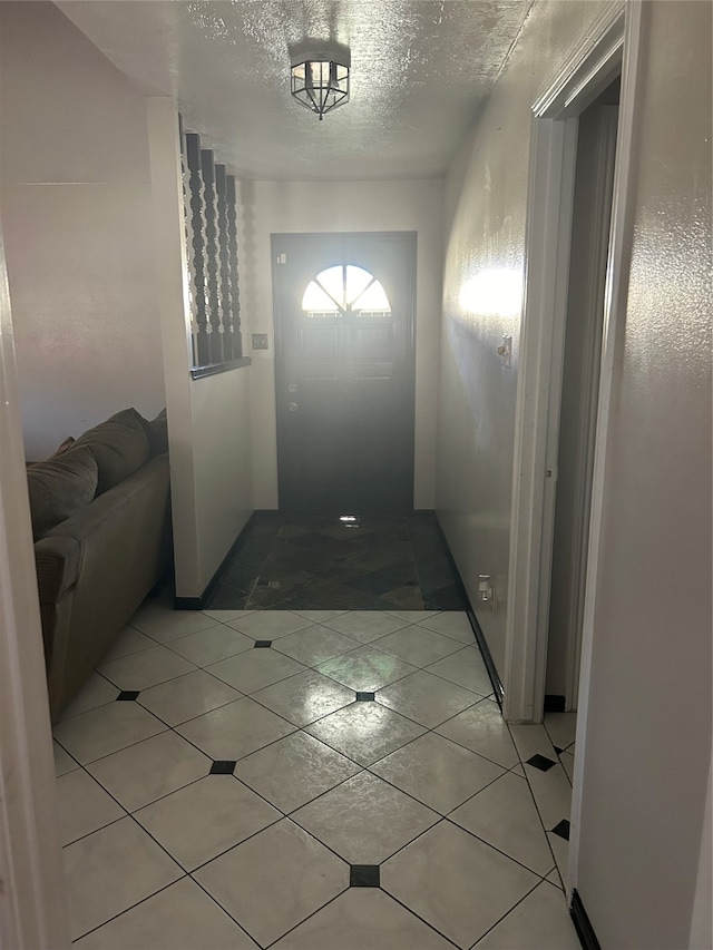 corridor featuring a textured ceiling and light tile patterned floors