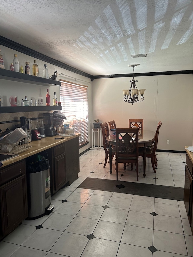 kitchen with a textured ceiling, light tile patterned flooring, hanging light fixtures, an inviting chandelier, and ornamental molding