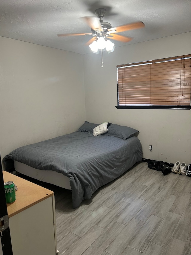 bedroom with light wood-type flooring, a textured ceiling, and ceiling fan