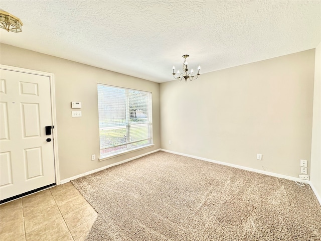 carpeted spare room featuring a textured ceiling and a notable chandelier