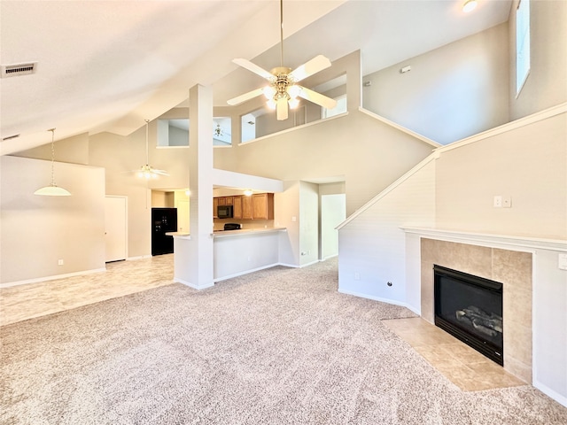 unfurnished living room featuring high vaulted ceiling, ceiling fan, a tile fireplace, and light carpet