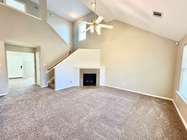 unfurnished living room with ceiling fan, carpet flooring, high vaulted ceiling, and a tile fireplace