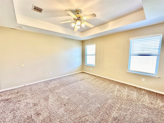 unfurnished room with ceiling fan, a textured ceiling, a raised ceiling, and carpet flooring