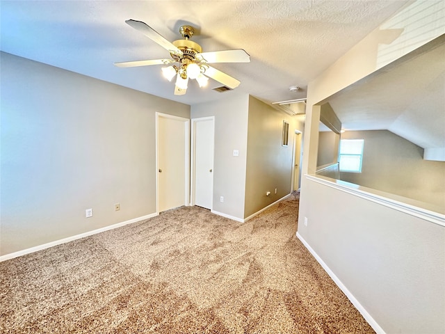 interior space featuring lofted ceiling, ceiling fan, carpet flooring, and a textured ceiling