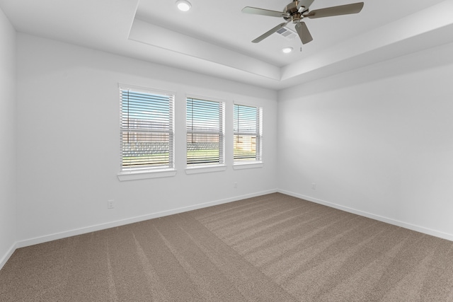 carpeted empty room featuring a tray ceiling and ceiling fan