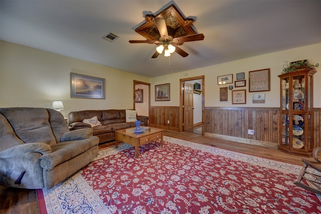 living room featuring light hardwood / wood-style floors, ceiling fan, and wood walls