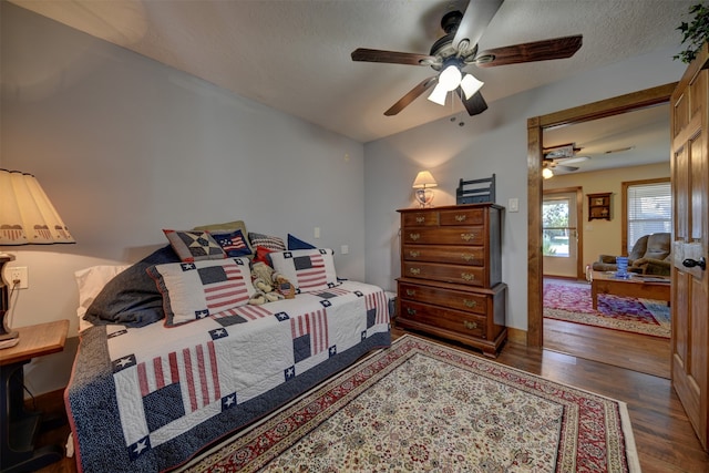 bedroom with a textured ceiling, ceiling fan, and dark hardwood / wood-style flooring