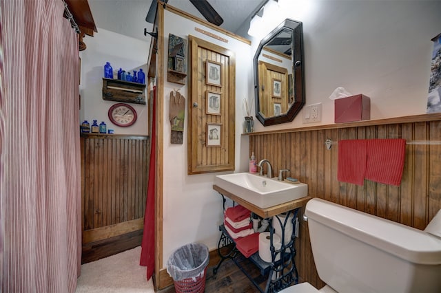 bathroom with a textured ceiling, wooden walls, and toilet