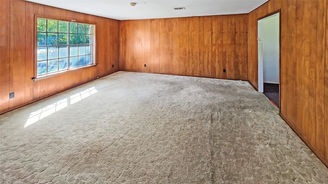 carpeted empty room featuring wooden walls