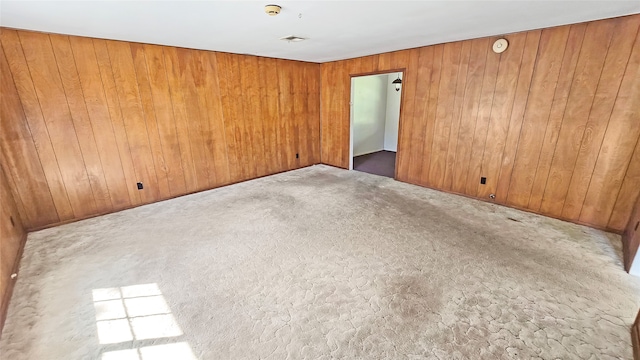 carpeted empty room featuring wooden walls