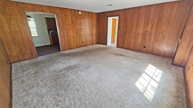 unfurnished bedroom featuring wooden walls and carpet