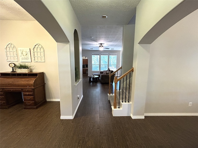 corridor with a textured ceiling and dark hardwood / wood-style flooring