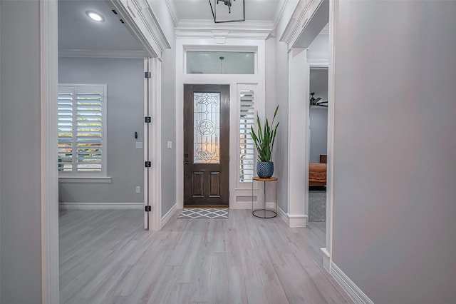 foyer entrance with ceiling fan, ornamental molding, and light wood-type flooring