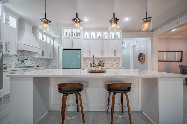 kitchen featuring a spacious island, pendant lighting, stainless steel gas cooktop, custom range hood, and white cabinets