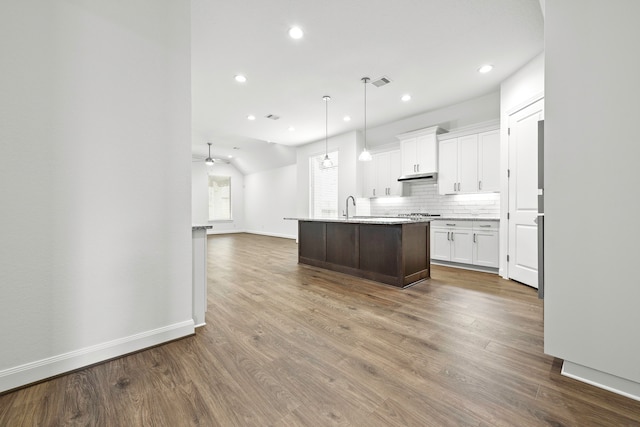 kitchen with an island with sink, white cabinetry, ceiling fan, decorative light fixtures, and dark hardwood / wood-style floors