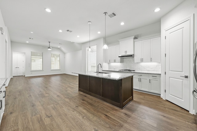 kitchen featuring stainless steel gas cooktop, dark wood-type flooring, white cabinetry, light stone counters, and ceiling fan