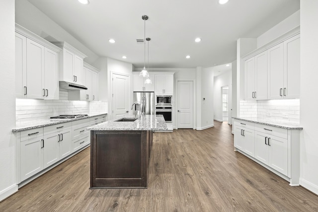 kitchen featuring light stone counters, stainless steel appliances, decorative light fixtures, and white cabinets