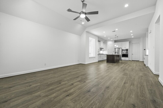 unfurnished living room with sink, ceiling fan, vaulted ceiling, and dark hardwood / wood-style flooring