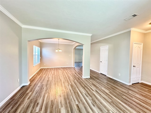 unfurnished room with ornamental molding, an inviting chandelier, and hardwood / wood-style floors