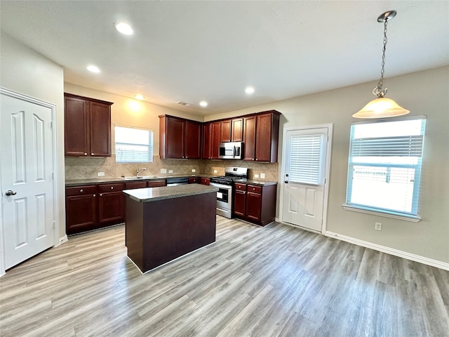 kitchen with stainless steel appliances, light hardwood / wood-style floors, tasteful backsplash, and a kitchen island