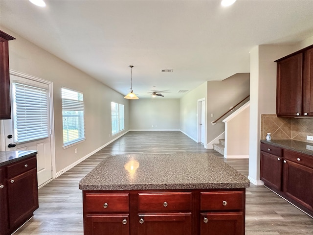 kitchen with ceiling fan, hardwood / wood-style flooring, backsplash, and a kitchen island