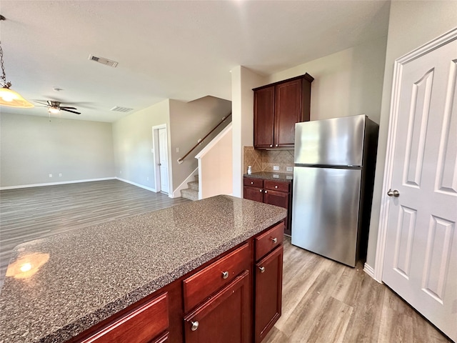 kitchen featuring light wood-type flooring, stainless steel fridge, backsplash, and ceiling fan