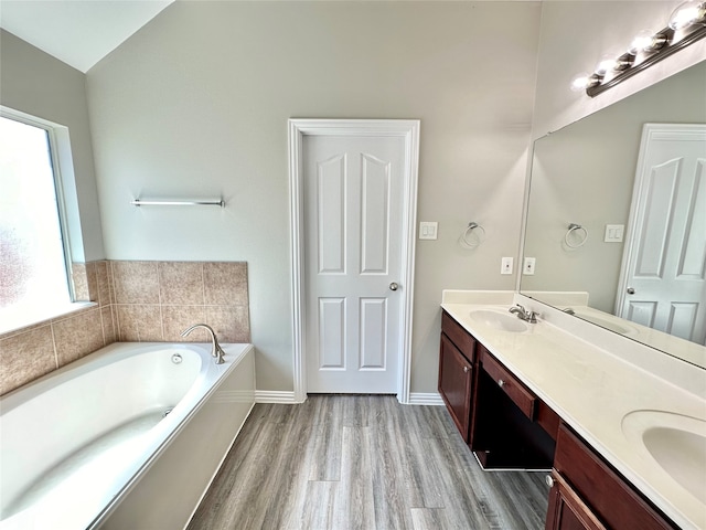 bathroom with a bath, vanity, vaulted ceiling, and hardwood / wood-style flooring