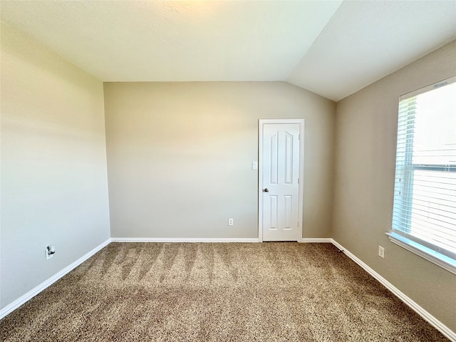 spare room featuring carpet flooring and vaulted ceiling