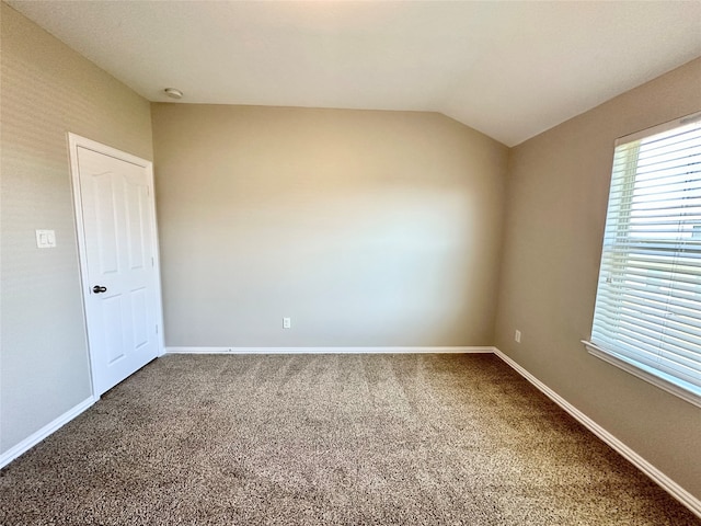 carpeted empty room featuring vaulted ceiling