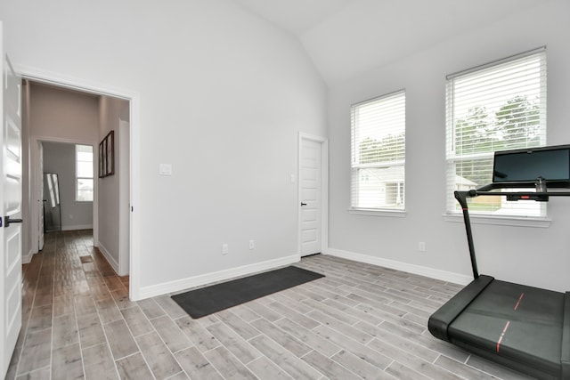 exercise room with light wood-type flooring and vaulted ceiling