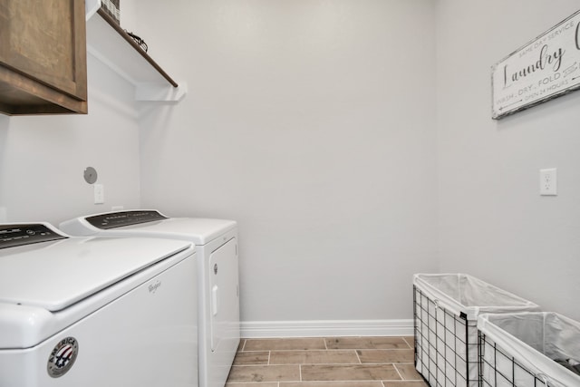 clothes washing area with cabinets and washing machine and dryer