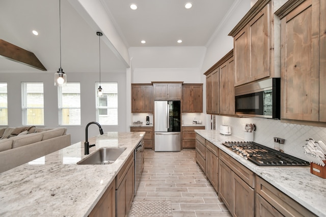 kitchen with appliances with stainless steel finishes, vaulted ceiling, light stone counters, pendant lighting, and sink