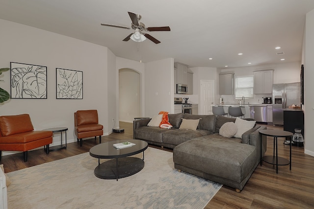 living room with dark hardwood / wood-style floors, ceiling fan, and sink