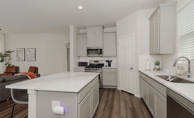 kitchen with appliances with stainless steel finishes, decorative backsplash, a breakfast bar area, dark hardwood / wood-style flooring, and sink