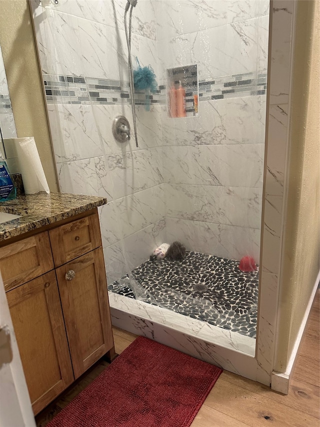 bathroom with wood-type flooring, vanity, and tiled shower