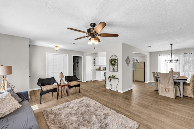 living room featuring wood-type flooring, a textured ceiling, and ceiling fan