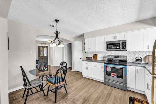 kitchen with hanging light fixtures, light hardwood / wood-style floors, white cabinetry, stainless steel appliances, and a chandelier