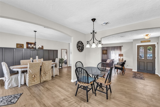 dining space featuring an inviting chandelier, light hardwood / wood-style flooring, and a textured ceiling