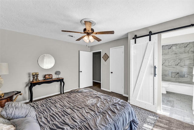 carpeted bedroom with ceiling fan, ensuite bathroom, a barn door, and a textured ceiling