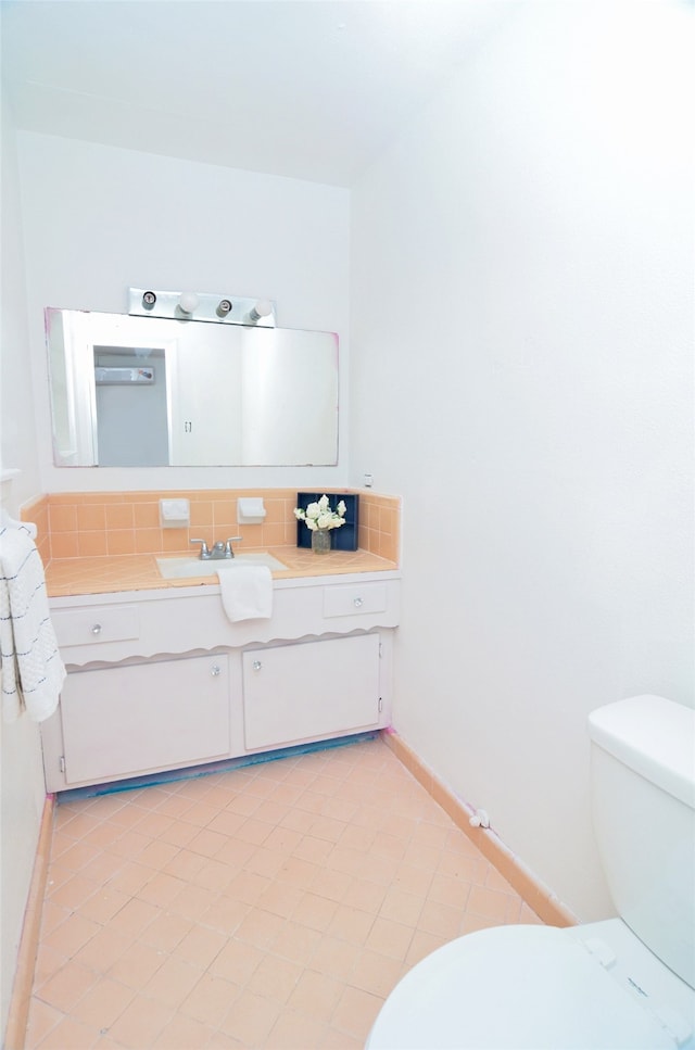 bathroom featuring vanity, toilet, and tasteful backsplash