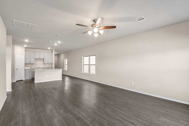 unfurnished living room featuring ceiling fan and dark hardwood / wood-style flooring