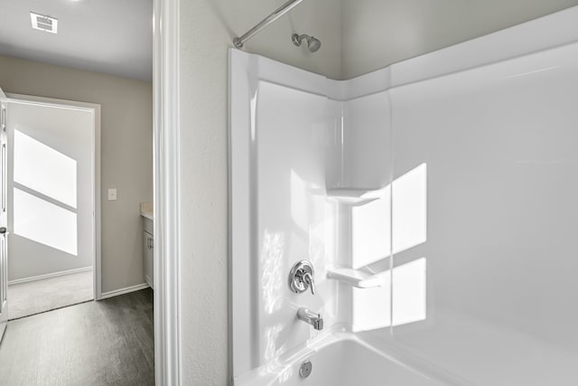 bathroom with hardwood / wood-style flooring, shower / washtub combination, and vanity