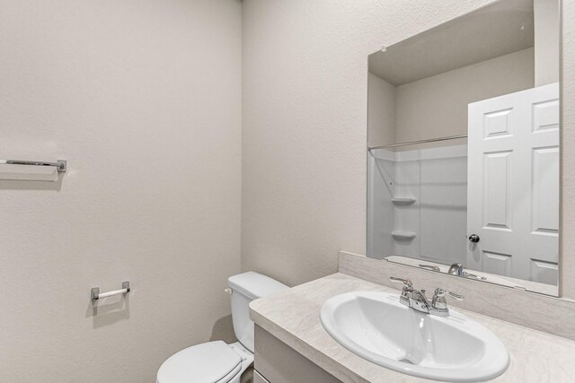 bathroom featuring walk in shower, vanity, and toilet