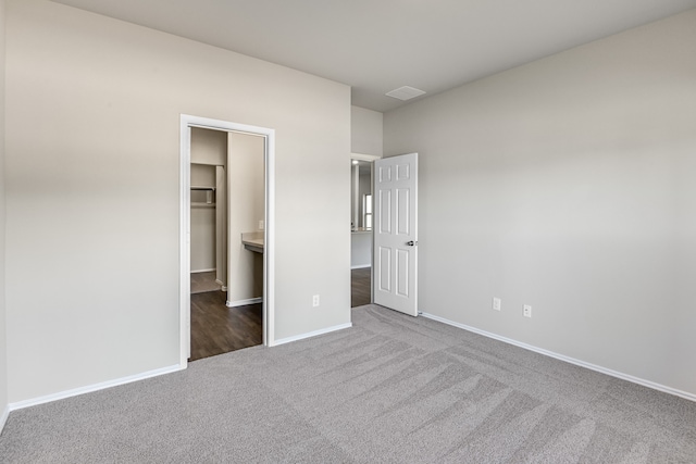 unfurnished bedroom with a spacious closet, dark colored carpet, and a closet