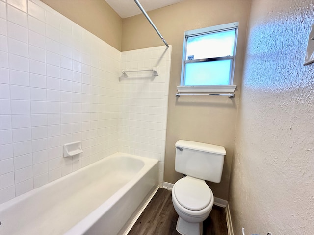 bathroom with tiled shower / bath, hardwood / wood-style flooring, and toilet