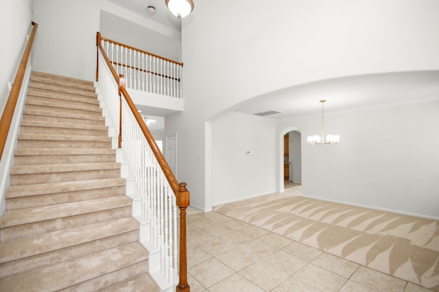 staircase featuring a high ceiling, tile patterned flooring, and a chandelier