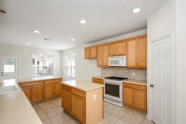 kitchen with decorative backsplash, light tile patterned flooring, white appliances, a center island, and sink